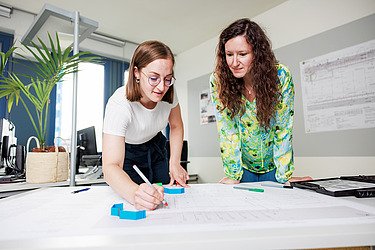 Zwei Mitarbeiterinnen betrachten eine bautechnische Zeichnung