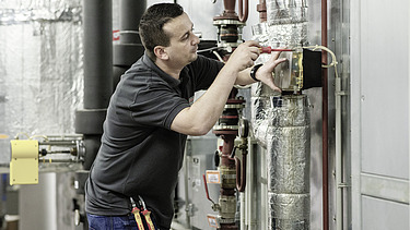 Foto Mitarbeiter arbeitet an Rohrleitungsanlage