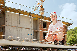 Foto Auszubildender vor einem Rohbau