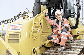 Foto Lehrling sitzt auf Baumaschine