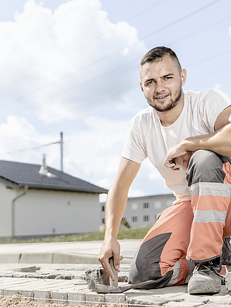 Bild eines Lehrlings, der auf der Baustelle pflastert