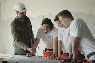 Foto drei Bauarbeiter mit Wasserwaage und Metallgerüst 