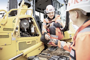 Foto ein Bauarbeiter und eine Bauarbeiterin vor Baugerät