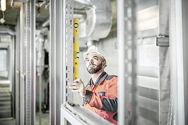 Foto Ein Mitarbeiter überprüft Metallelemente mit Wasserwaage