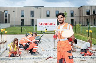 Foto Lehrling vor zu pflasternder Fläche